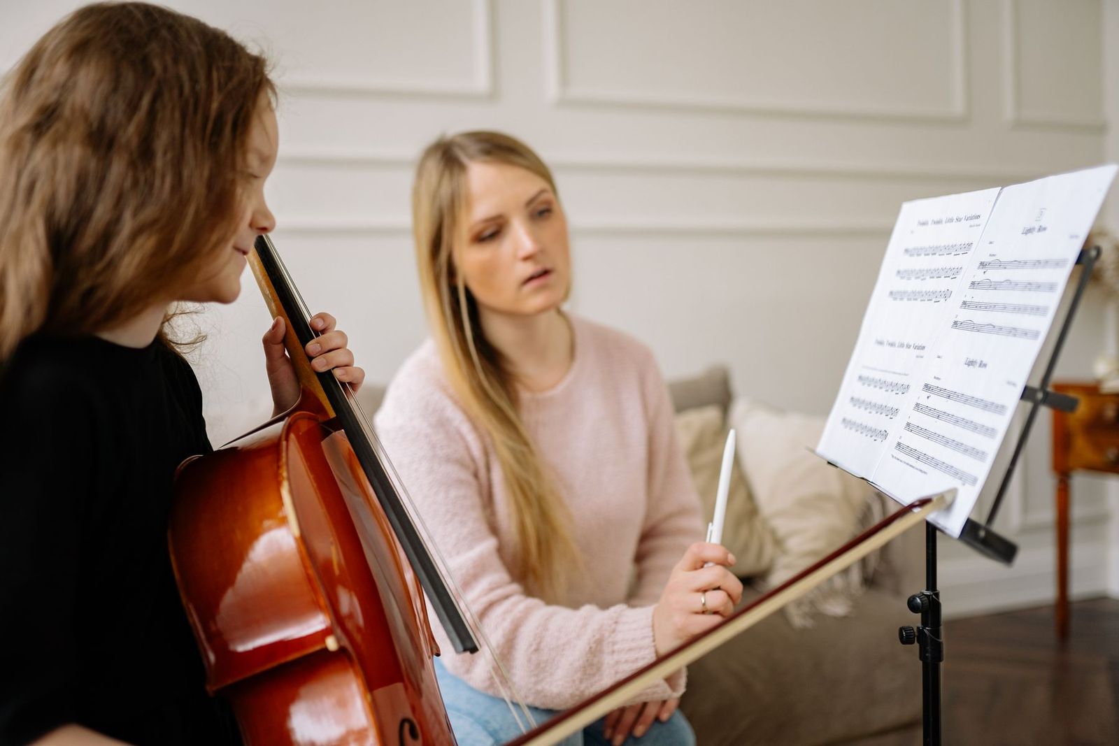 Lehrerin begleitet ein Kind beim Cellospielen