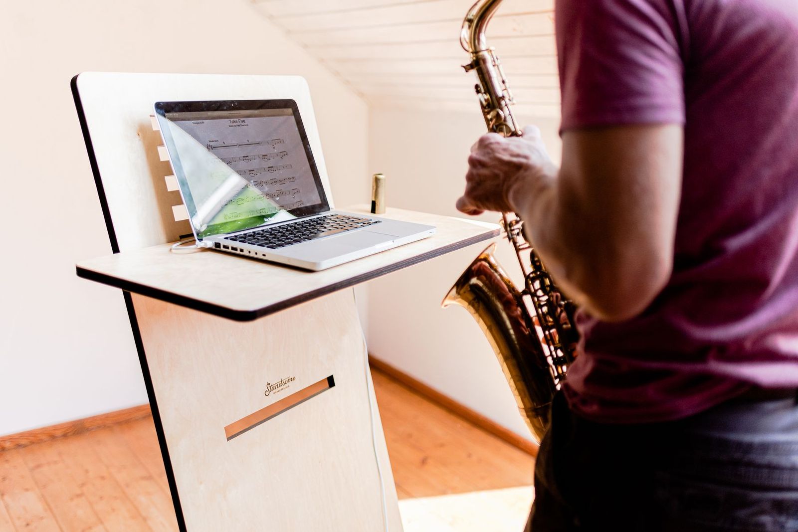 Musiker übt Saxofon mit Noten auf dem Laptop
