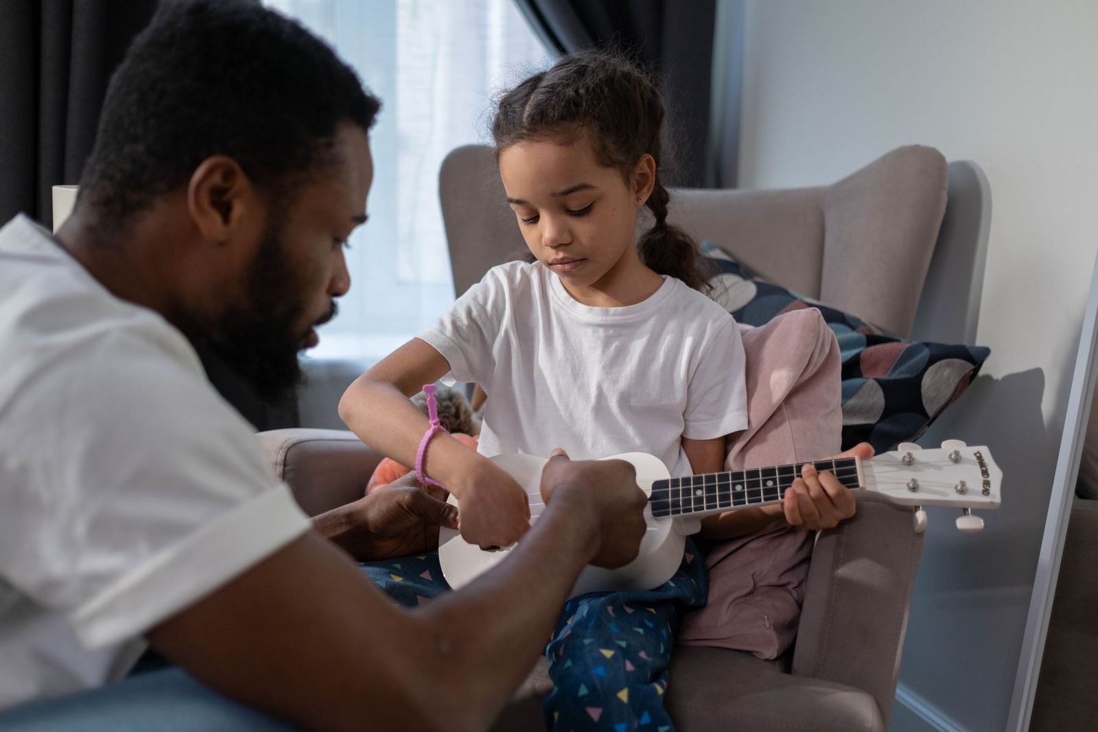 Vater und Tochter lernen zu Hause gemeinsam Ukulele